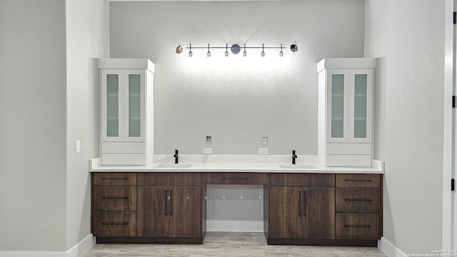 bathroom with double vanity, baseboards, a sink, and wood finished floors