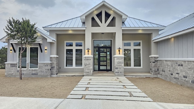 view of exterior entry with a standing seam roof, stone siding, and metal roof