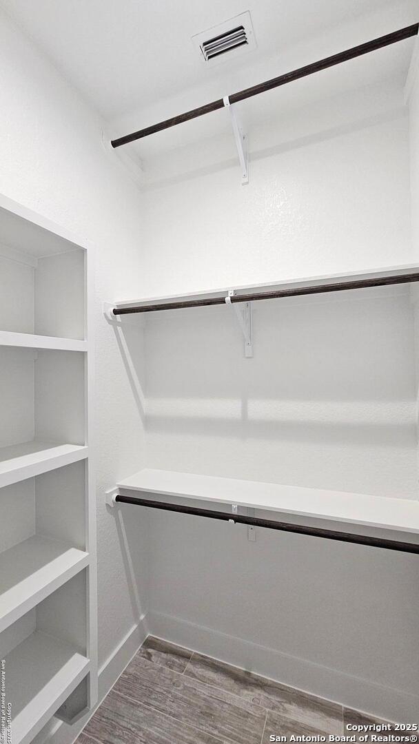 walk in closet featuring visible vents and dark wood finished floors