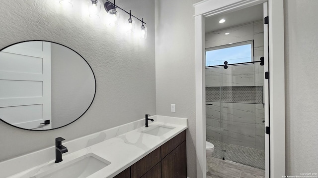 bathroom featuring toilet, a stall shower, double vanity, and a sink