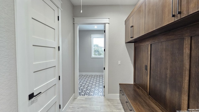 mudroom with attic access and baseboards