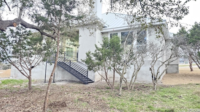 view of side of property with metal roof, stairway, and stucco siding