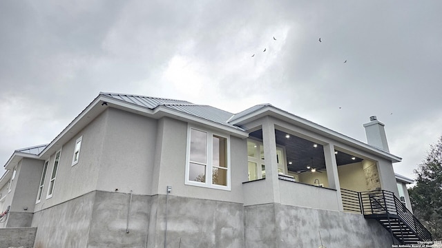 view of home's exterior featuring a standing seam roof, metal roof, a chimney, and stucco siding