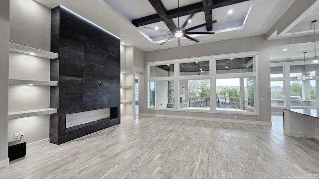 unfurnished living room with baseboards, coffered ceiling, a tile fireplace, wood finished floors, and a chandelier