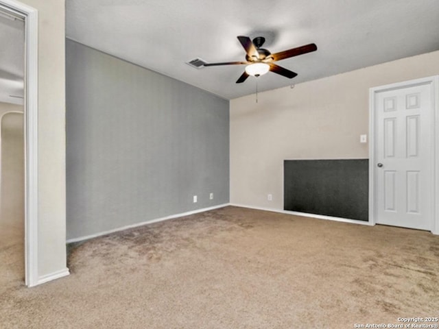 unfurnished room with baseboards, a fireplace, a ceiling fan, and carpet flooring