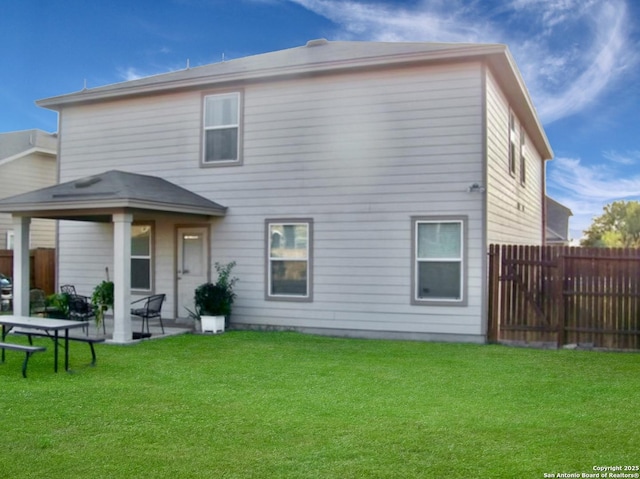 back of house featuring a lawn, a patio area, and fence