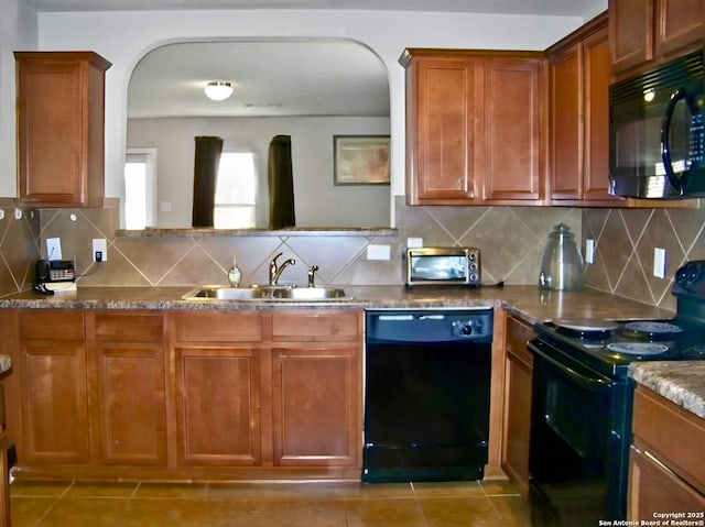 kitchen featuring tasteful backsplash, a toaster, brown cabinetry, black appliances, and a sink