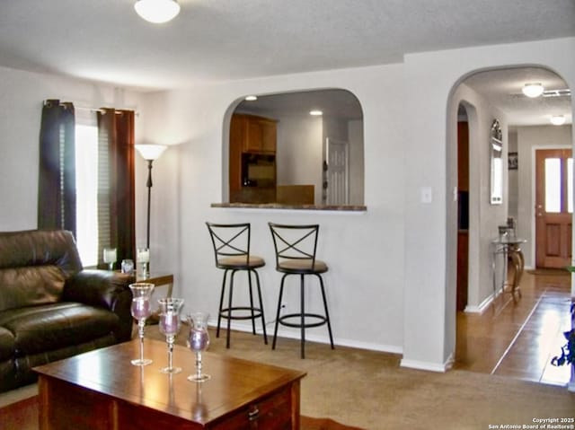 carpeted living area with arched walkways and baseboards