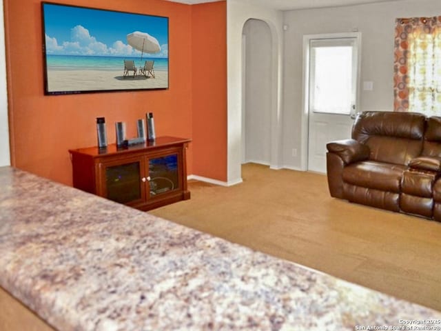 carpeted living area with arched walkways and baseboards