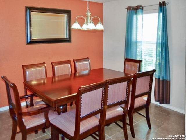 tiled dining room with baseboards and a chandelier