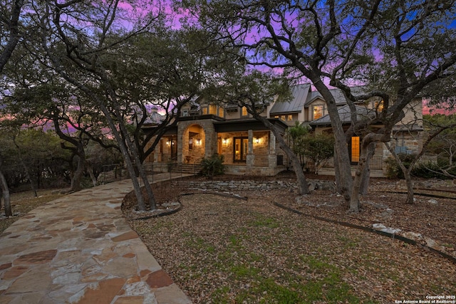 view of front facade with stone siding, metal roof, concrete driveway, and a standing seam roof