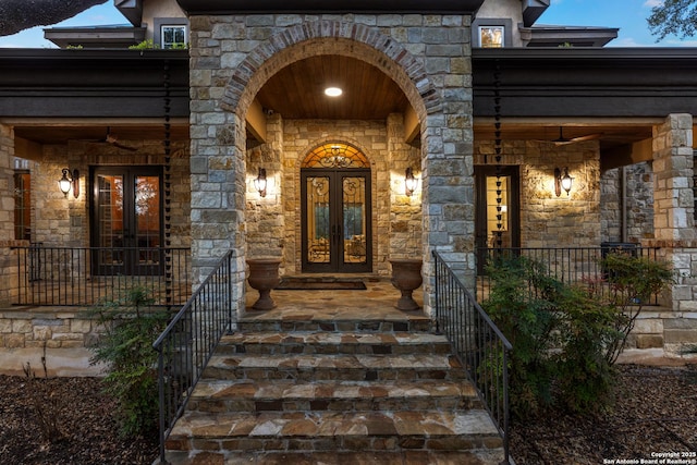 doorway to property featuring a ceiling fan, french doors, and stone siding