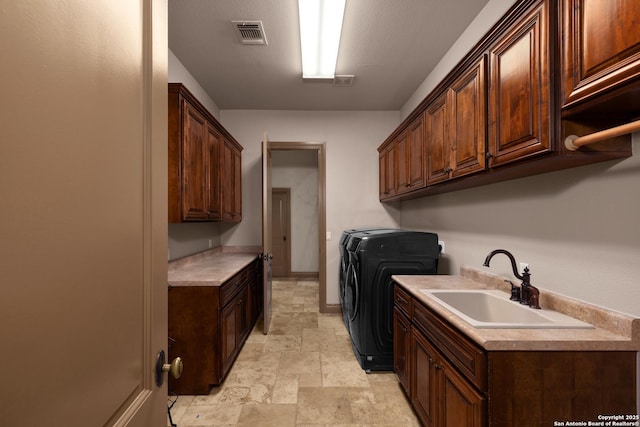 laundry room with a sink, visible vents, cabinet space, stone finish flooring, and washer and clothes dryer