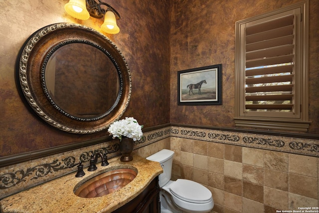 bathroom featuring tile walls, a wainscoted wall, vanity, and toilet