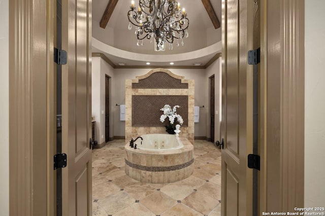 bathroom with beam ceiling, an inviting chandelier, ornamental molding, a jetted tub, and baseboards