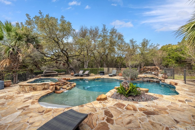 view of swimming pool featuring a pool with connected hot tub, fence, and a patio