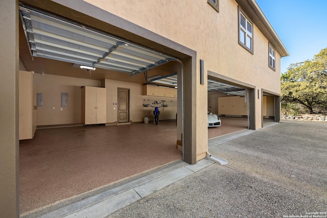 garage featuring driveway, electric panel, and a garage door opener