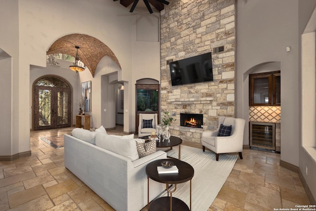 living room featuring baseboards, a high ceiling, a fireplace, and stone tile floors