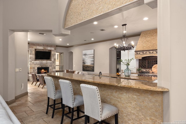 kitchen with recessed lighting, a fireplace, baseboards, ornamental molding, and stone tile flooring