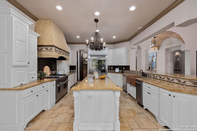 kitchen with appliances with stainless steel finishes, recessed lighting, custom range hood, and stone tile floors