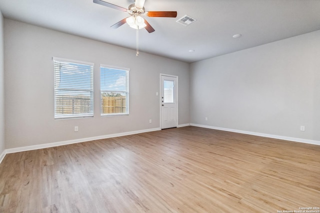 unfurnished room with a ceiling fan, visible vents, light wood finished floors, and baseboards