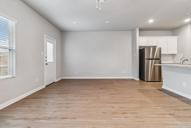 kitchen featuring light wood finished floors, recessed lighting, freestanding refrigerator, and white cabinets