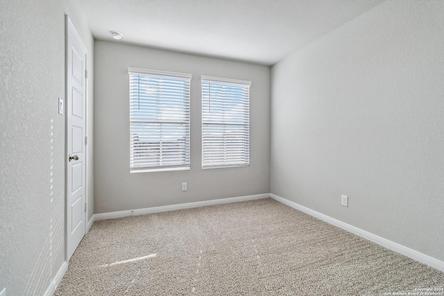 unfurnished room featuring carpet and baseboards