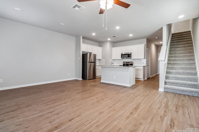 kitchen with stainless steel appliances, light countertops, visible vents, light wood-style flooring, and open floor plan