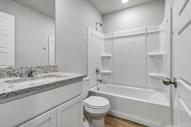 full bathroom featuring a textured wall, toilet, wood finished floors,  shower combination, and vanity