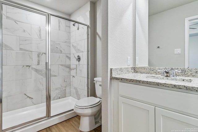 full bath featuring vanity, wood finished floors, a shower stall, and toilet