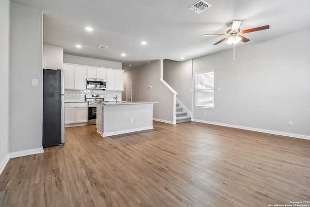 kitchen with open floor plan, stainless steel appliances, visible vents, and light wood-style floors