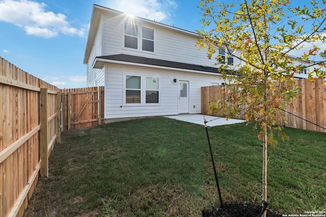 rear view of house featuring a yard, a patio, and a fenced backyard