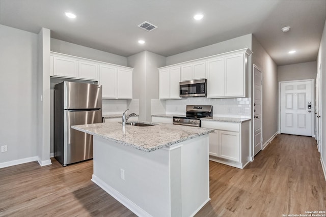 kitchen featuring visible vents, appliances with stainless steel finishes, white cabinets, and a sink