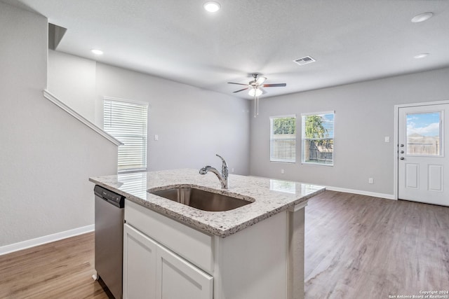 kitchen with a sink, visible vents, white cabinets, light wood-style floors, and dishwasher