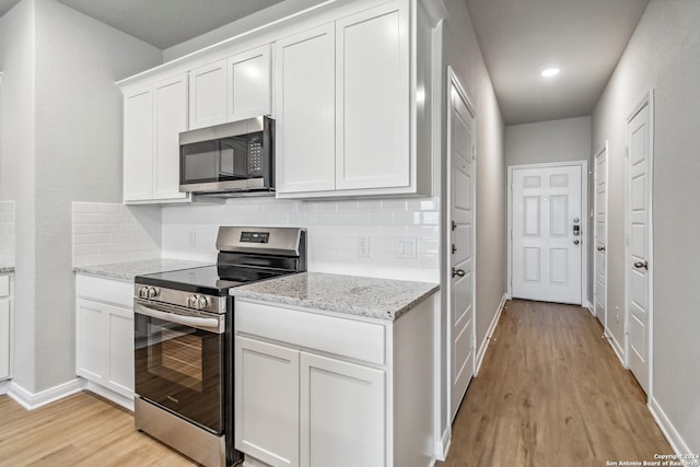 kitchen with appliances with stainless steel finishes, white cabinetry, light wood-style flooring, and decorative backsplash