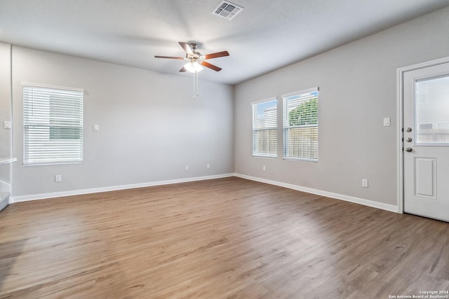 empty room featuring visible vents, ceiling fan, baseboards, and wood finished floors