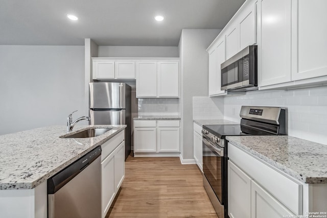 kitchen featuring stainless steel appliances, light wood-style floors, white cabinetry, and a sink