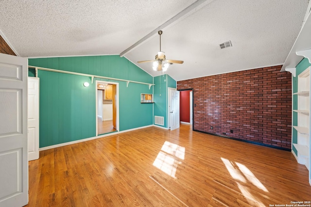 unfurnished bedroom with vaulted ceiling with beams, a textured ceiling, wood finished floors, and visible vents