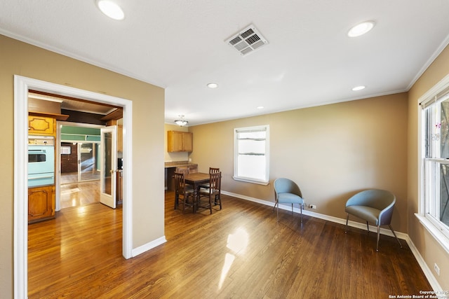 living area with a healthy amount of sunlight, baseboards, visible vents, and wood finished floors