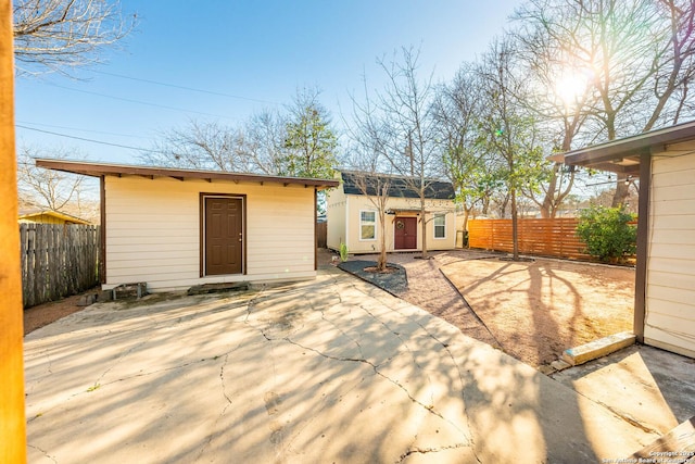 rear view of property featuring an outbuilding, a fenced backyard, and a patio