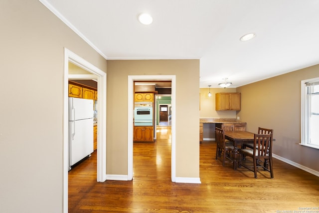 dining room featuring crown molding, baseboards, wood finished floors, and recessed lighting