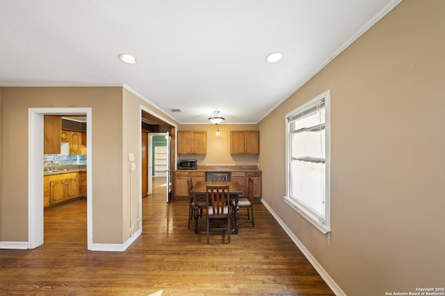 kitchen featuring crown molding, recessed lighting, stainless steel microwave, wood finished floors, and baseboards