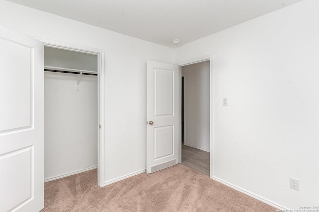 unfurnished bedroom featuring carpet, baseboards, and a closet