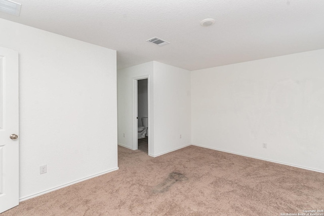 empty room featuring a textured ceiling, carpet flooring, and visible vents