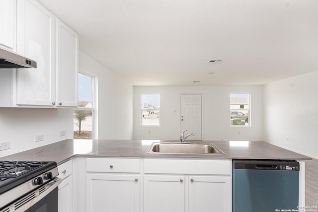 kitchen with dishwashing machine, stainless steel gas range oven, a peninsula, a sink, and white cabinets