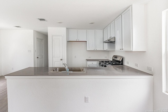 kitchen featuring stainless steel gas stove, visible vents, a peninsula, under cabinet range hood, and a sink