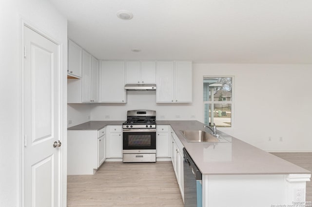 kitchen with stainless steel appliances, a sink, a peninsula, and light wood finished floors