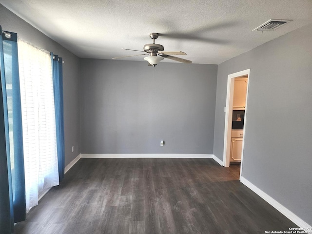 unfurnished room with ceiling fan, a textured ceiling, dark wood-style flooring, visible vents, and baseboards