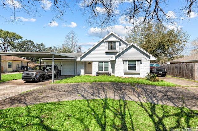 view of front facade with concrete driveway, brick siding, fence, and a front lawn