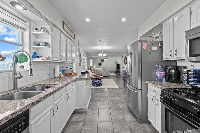 kitchen featuring appliances with stainless steel finishes, open floor plan, white cabinetry, a sink, and a chandelier